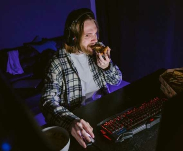man eating pizza playing games