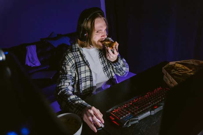 man eating pizza playing games