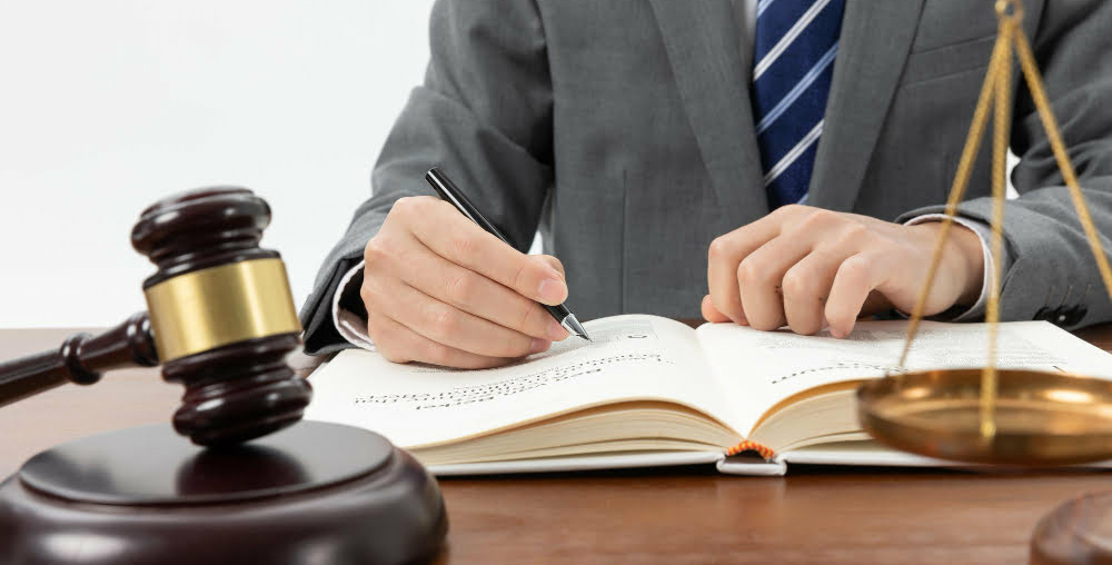 closeup-shot-person-writing-book-with-gavel-table (1)