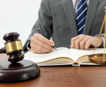 closeup-shot-person-writing-book-with-gavel-table (1)